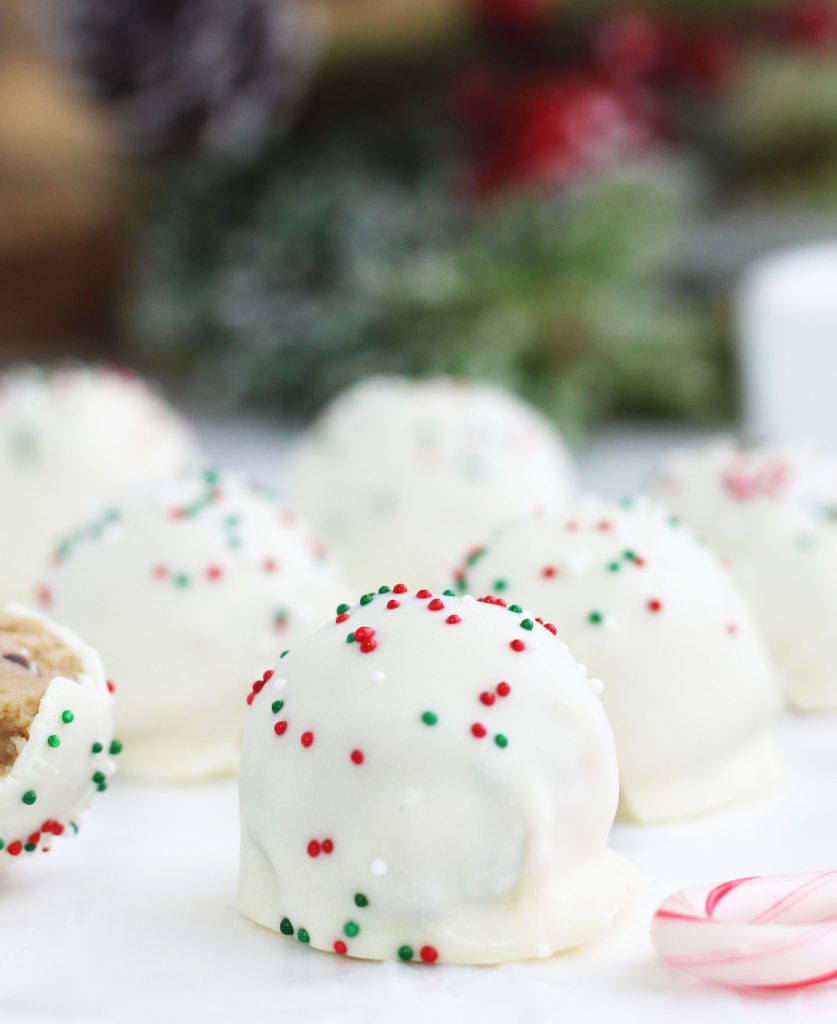These Chocolate Chip Cookie Dough Truffles require no baking and are so festive for Christmas with a white chocolate topping and colored sprinkles.  The cookie dough batter is safe for consumption with no eggs and microwaved flour.
