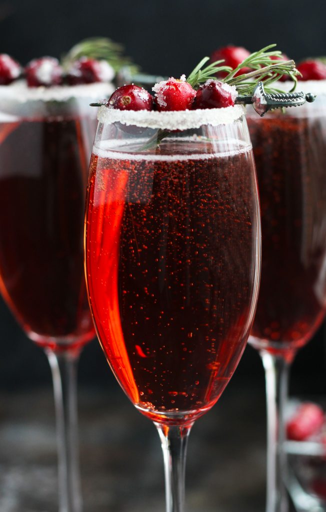 This Cranberry Mimosa gets orange liqueur and is topped with sugared cranberries and rosemary for a festive, holiday cocktail.