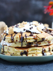 These S'mores Pancakes are pure breakfast bliss with Golden Grahams and chocolate chips in the batter.  A generous topping of marshmallow cream, chocolate sauce, more cereal and chocolate chips makes this better than the campfire version.