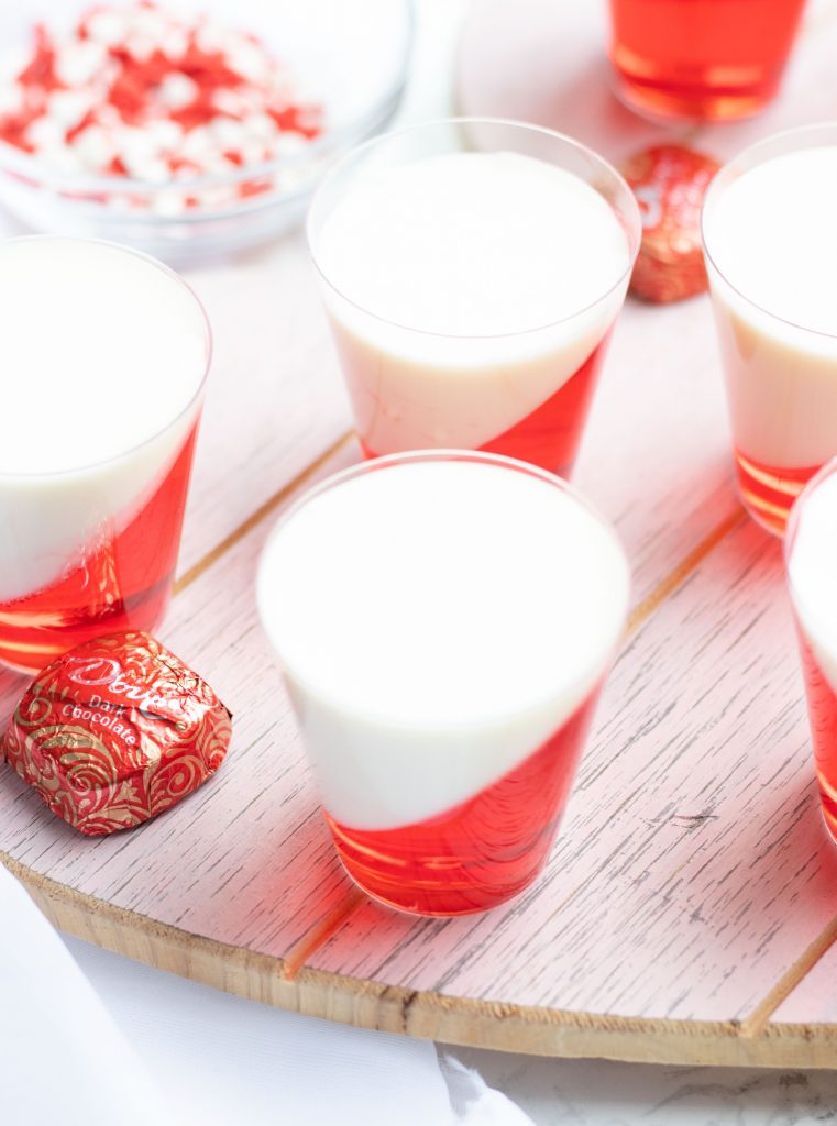 These Strawberries and Cream Layered Jell-O Shots are a festive Valentine's Day treat with whipped cream vodka.  A heart made out of melted white chocolate and sugar sprinkles makes the perfect topper.
