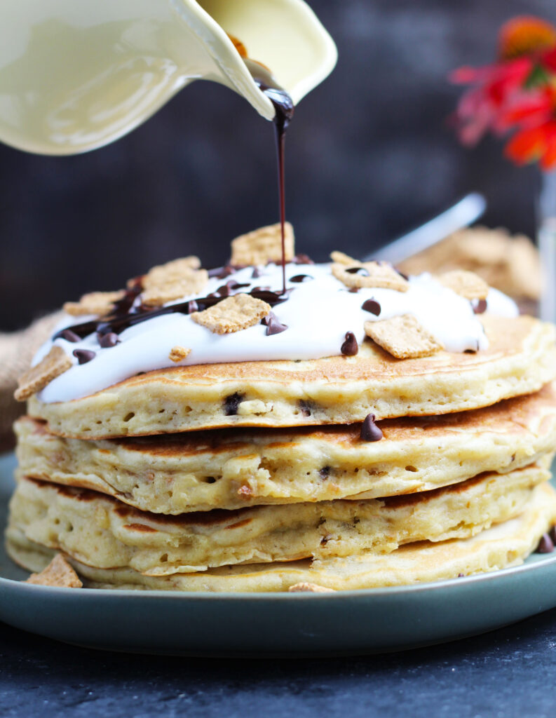 These S'mores Pancakes are pure breakfast bliss with Golden Grahams and chocolate chips in the batter.  A generous topping of marshmallow cream, chocolate sauce, more cereal and chocolate chips makes these better than the campfire version.