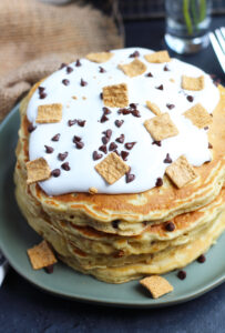 These S'mores Pancakes are pure breakfast bliss with Golden Grahams and chocolate chips in the batter.  A generous topping of marshmallow cream, chocolate sauce, more cereal and chocolate chips makes these better than the campfire version.