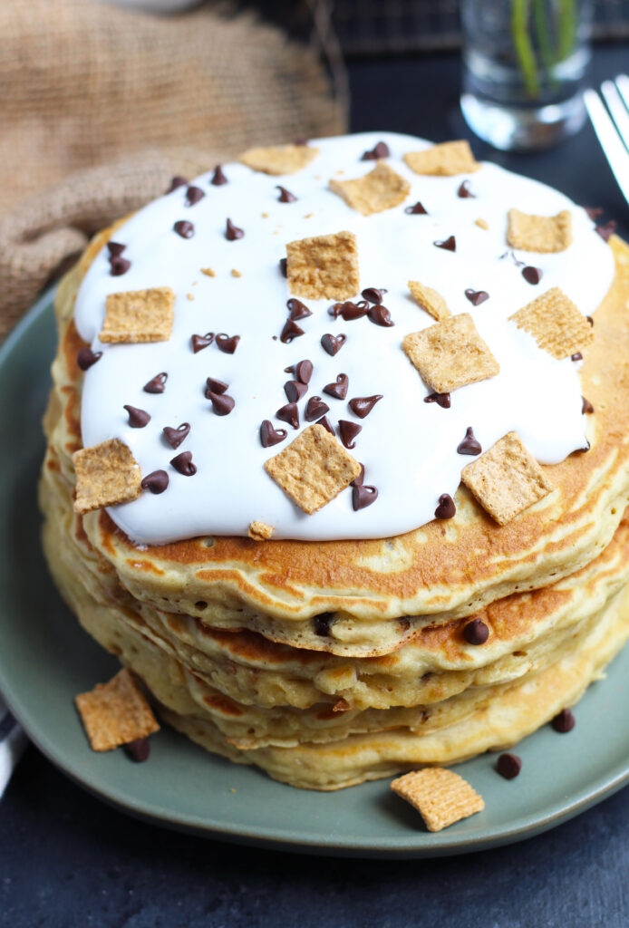 These S'mores Pancakes are pure breakfast bliss with Golden Grahams and chocolate chips in the batter.  A generous topping of marshmallow cream, chocolate sauce, more cereal and chocolate chips makes these better than the campfire version.