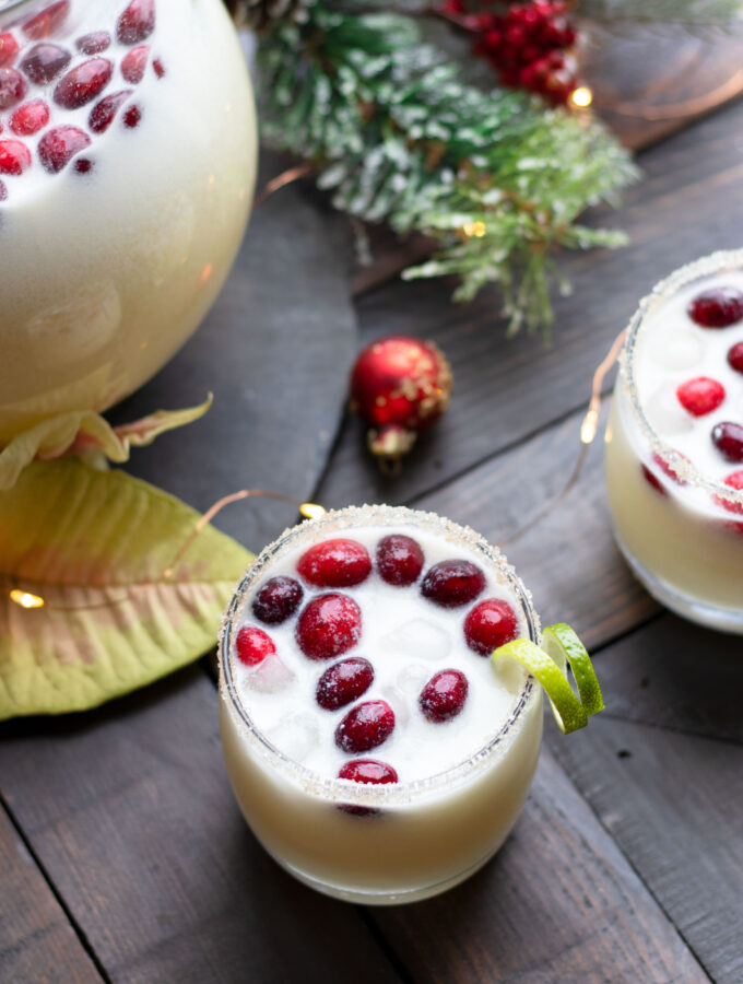 This Holiday Coconut Margarita Pitcher is perfect for entertaining guests throughout the winter.  Fresh cranberries and a sugared rim complete this margarita with tequila, white cranberry juice, Malibu, fresh lime juice, orange juice and coconut milk.