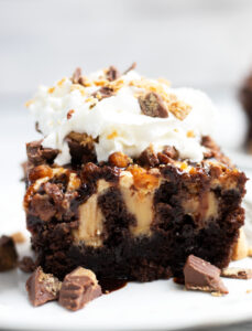 This Chocolate Peanut Butter Poke cake is so easy to make with box cake mix, chocolate fudge, vanilla pudding and plenty of peanut butter cups.